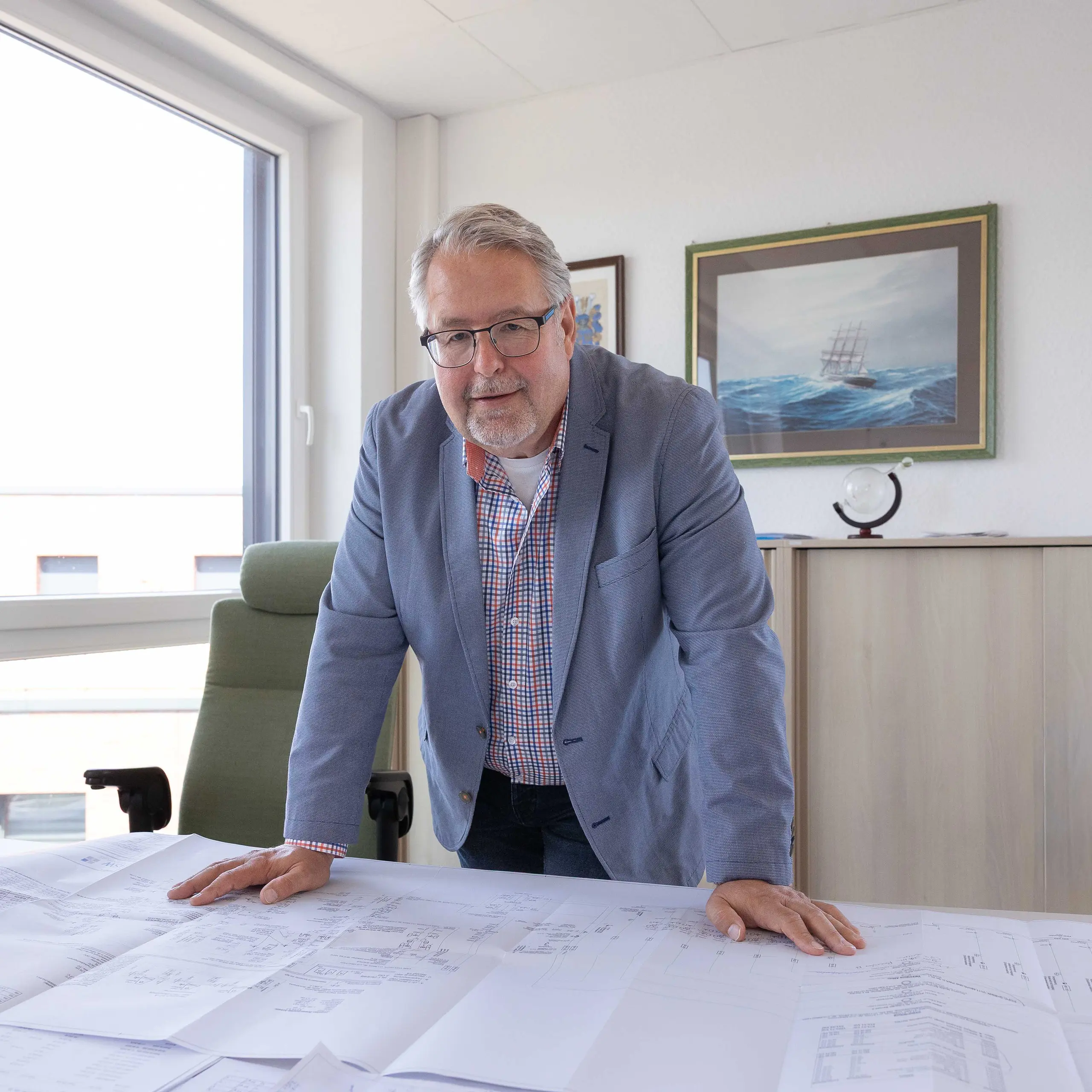 Ulf Schnittger Ulf Schnittger stützt sich auf seinem Schreibtisch ab und lächelt in die Kamera.