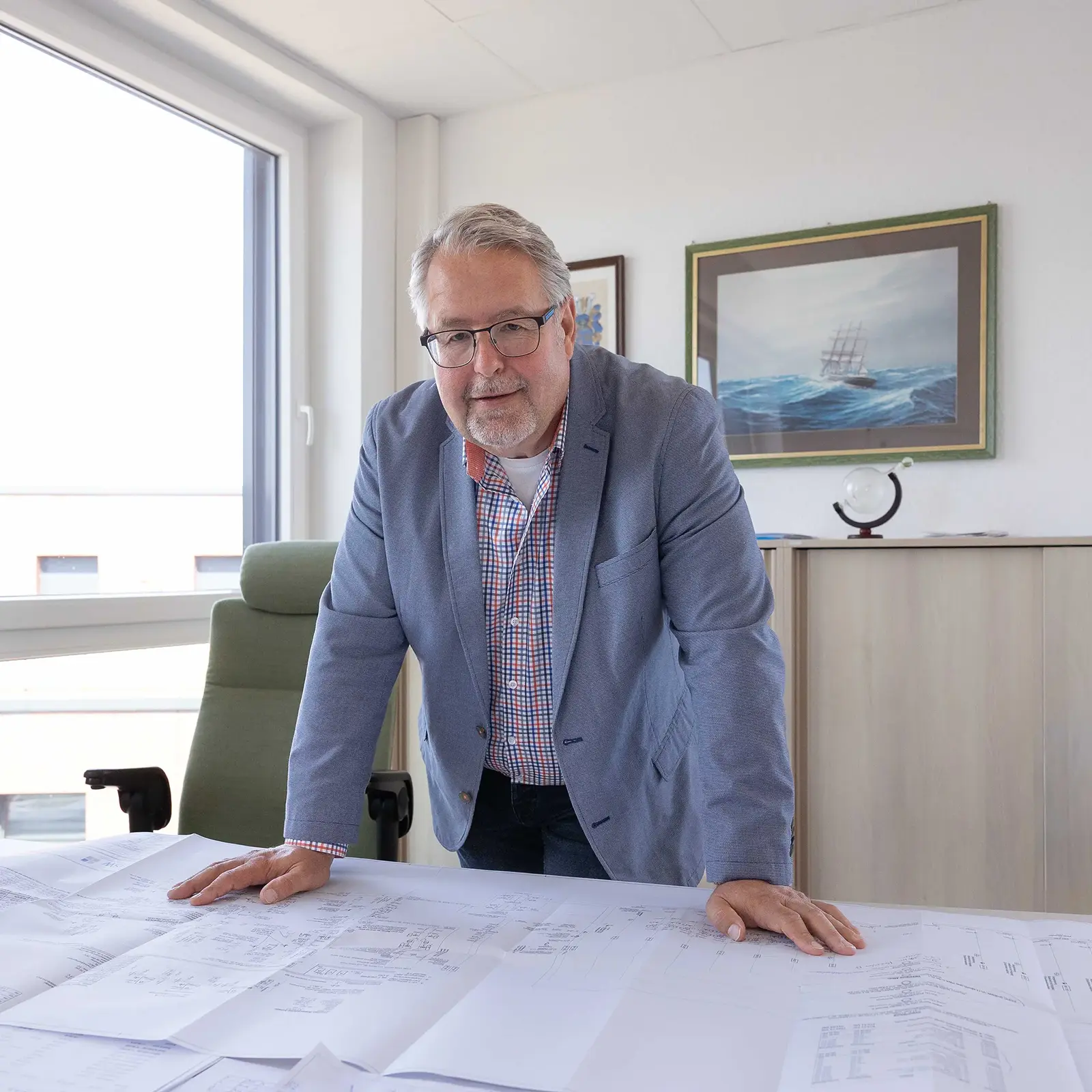 Ulf Schnittger Ulf Schnittger stützt sich auf seinem Schreibtisch ab und lächelt in die Kamera