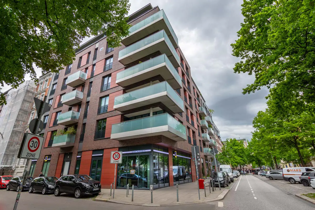 sechsstöckiges Haus mit dem Namen Maxliving aus der Perspektive über Eck mit großen Balkonen mit Glaswänden an der Ecke