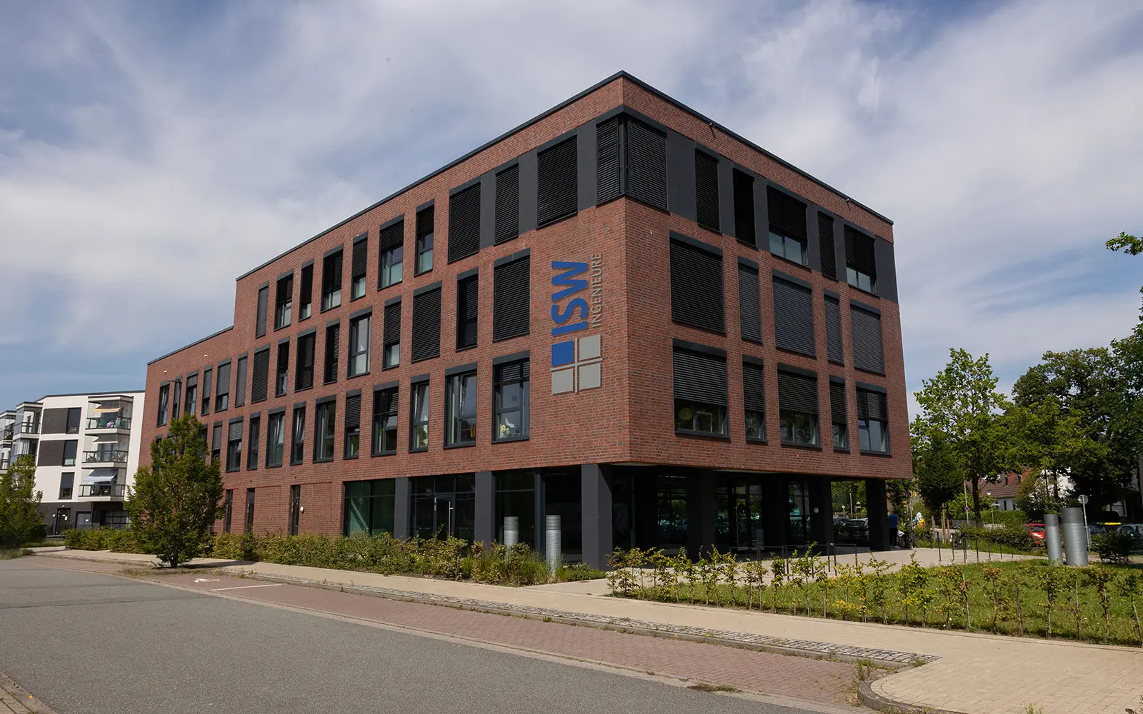 Blick von der Straße auf ein rotes viergeschossiges Backstein Gebäude mit dem Logo von ISW drauf